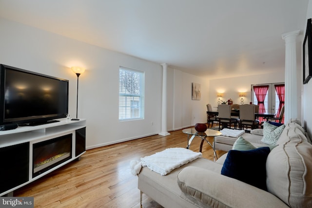 living room featuring ornate columns, a wealth of natural light, and wood finished floors