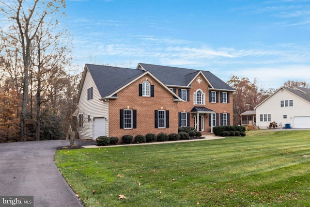 view of front of home featuring a garage, a front yard, aphalt driveway, and brick siding