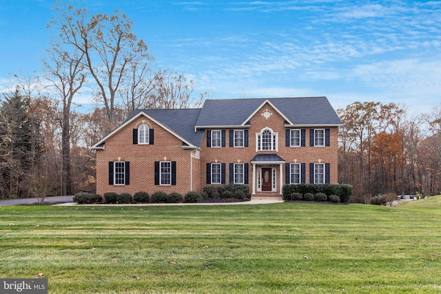 colonial inspired home featuring brick siding and a front lawn