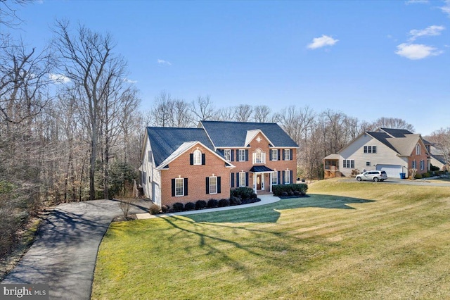 view of front of home featuring a front lawn, brick siding, and aphalt driveway