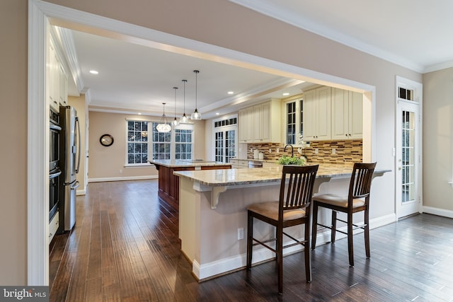 kitchen with a peninsula, tasteful backsplash, a breakfast bar area, and crown molding