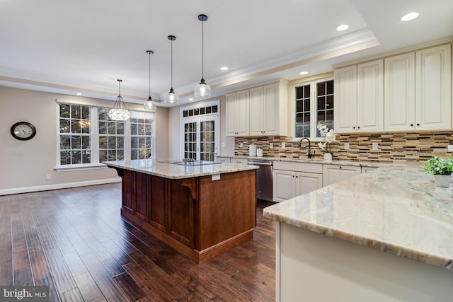 kitchen featuring light stone counters, a raised ceiling, decorative backsplash, stainless steel dishwasher, and a sink