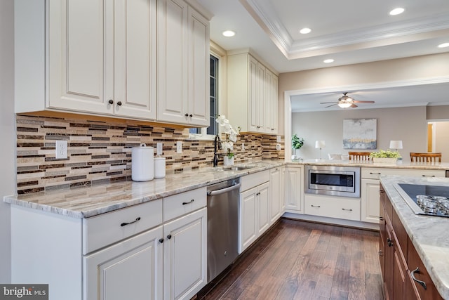 kitchen with light stone counters, dark wood-style floors, crown molding, stainless steel appliances, and a sink