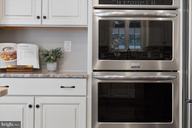 kitchen featuring light stone countertops, double oven, and white cabinetry