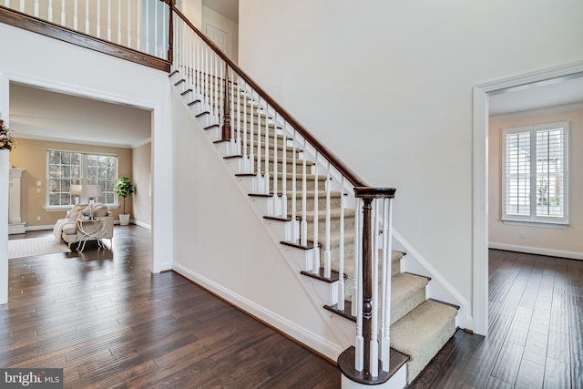 stairs featuring baseboards, plenty of natural light, wood finished floors, and crown molding