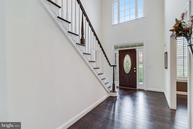 entrance foyer featuring a wealth of natural light, a towering ceiling, hardwood / wood-style flooring, and baseboards