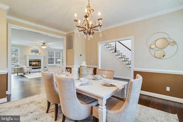 dining area featuring a warm lit fireplace, wood-type flooring, and crown molding