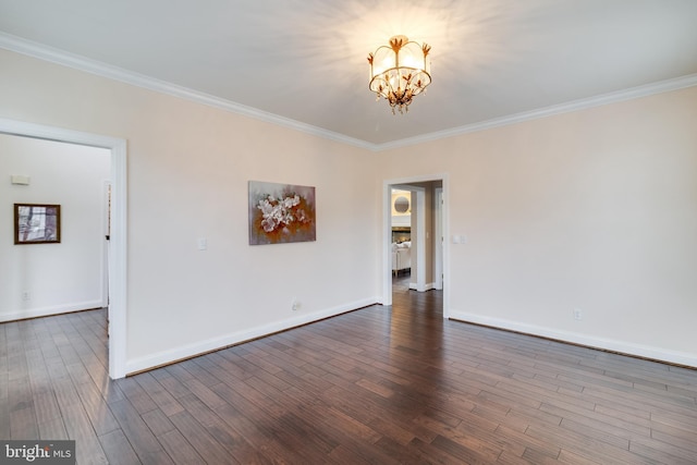 empty room with a notable chandelier, ornamental molding, wood finished floors, and baseboards