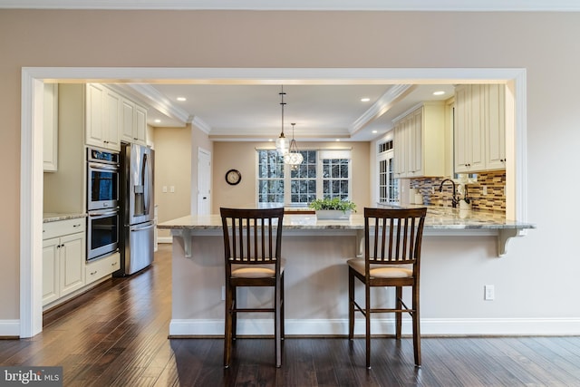 kitchen with stainless steel appliances, ornamental molding, a peninsula, and decorative backsplash