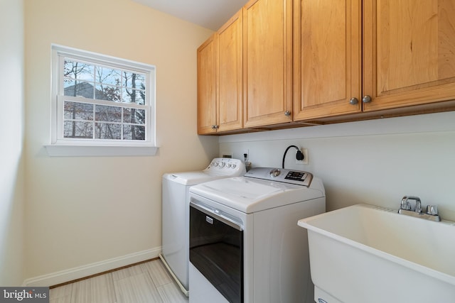 laundry room with cabinet space, baseboards, washer and dryer, and a sink