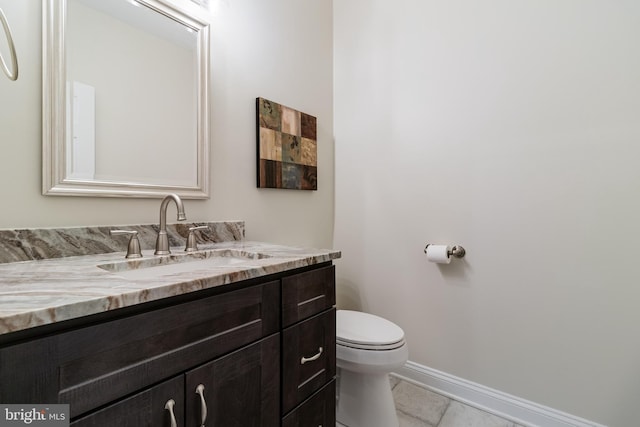 half bathroom featuring baseboards, vanity, and toilet