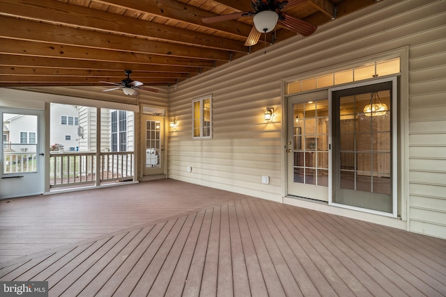 unfurnished sunroom featuring a ceiling fan, wood ceiling, and beam ceiling