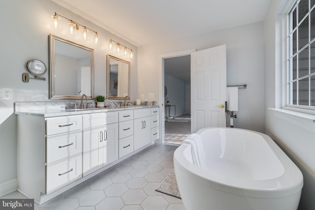 bathroom with double vanity, a freestanding tub, tile patterned flooring, and a sink