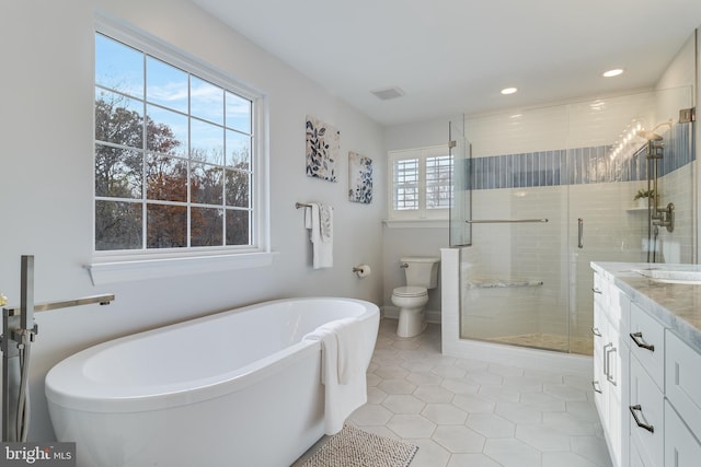 bathroom featuring toilet, vanity, a soaking tub, a shower stall, and tile patterned floors