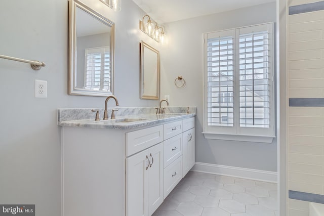 full bathroom with double vanity, baseboards, a sink, and tile patterned floors