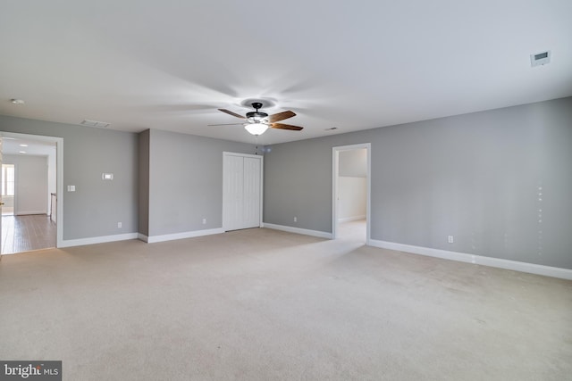 unfurnished room featuring light carpet, a ceiling fan, visible vents, and baseboards