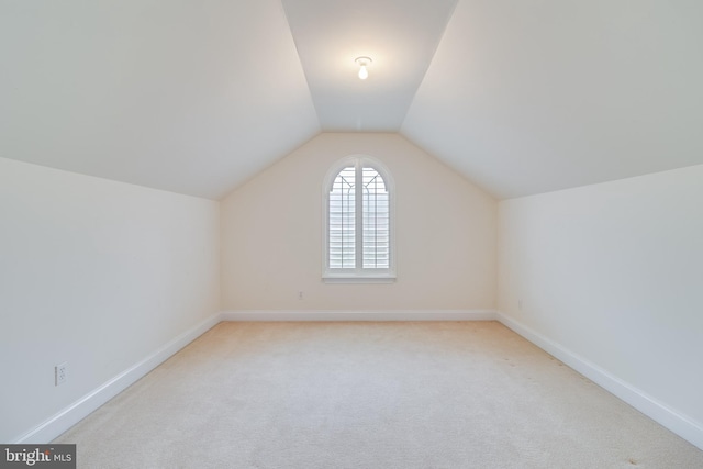 bonus room featuring light colored carpet, vaulted ceiling, and baseboards