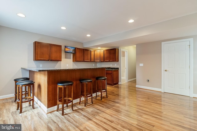 kitchen with recessed lighting, light wood-style flooring, and a kitchen breakfast bar