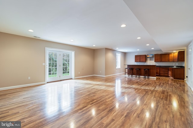 unfurnished living room featuring light wood-style floors, plenty of natural light, baseboards, and recessed lighting