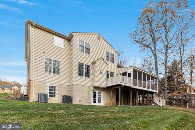 back of property featuring a sunroom, a yard, stairs, french doors, and central AC