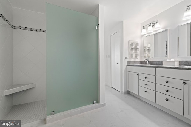 bathroom with marble finish floor, walk in shower, and vanity