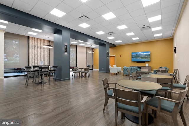 dining space featuring a paneled ceiling, visible vents, baseboards, and wood finished floors