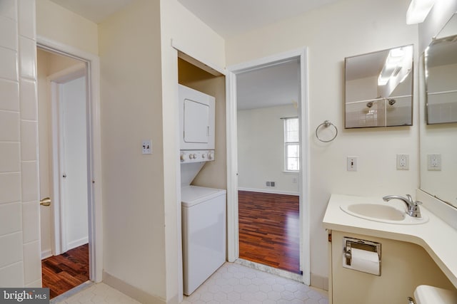 bathroom featuring baseboards, visible vents, stacked washer / drying machine, and wood finished floors