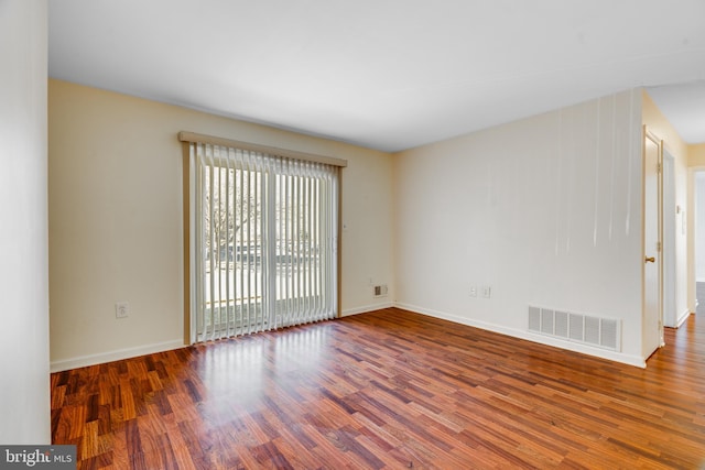 unfurnished room featuring wood finished floors, visible vents, and baseboards