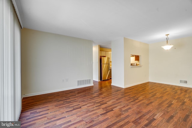 spare room with baseboards, visible vents, and dark wood-style flooring