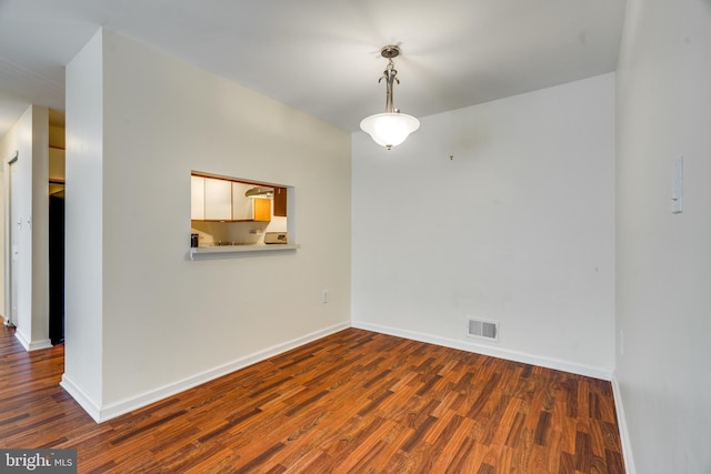 empty room with baseboards, visible vents, and wood finished floors