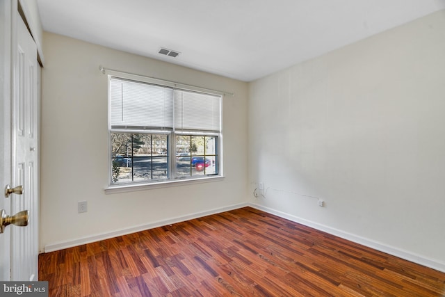 spare room with visible vents, baseboards, and wood finished floors