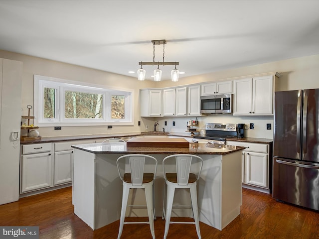 kitchen featuring a sink, dark wood-style floors, a kitchen island, and stainless steel appliances