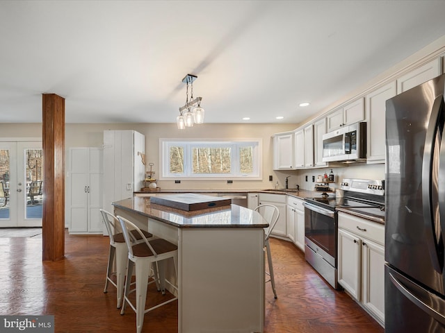 kitchen featuring decorative light fixtures, a kitchen breakfast bar, a center island, french doors, and appliances with stainless steel finishes