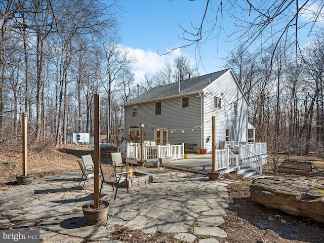 back of property featuring a patio, a fire pit, roof with shingles, and a deck