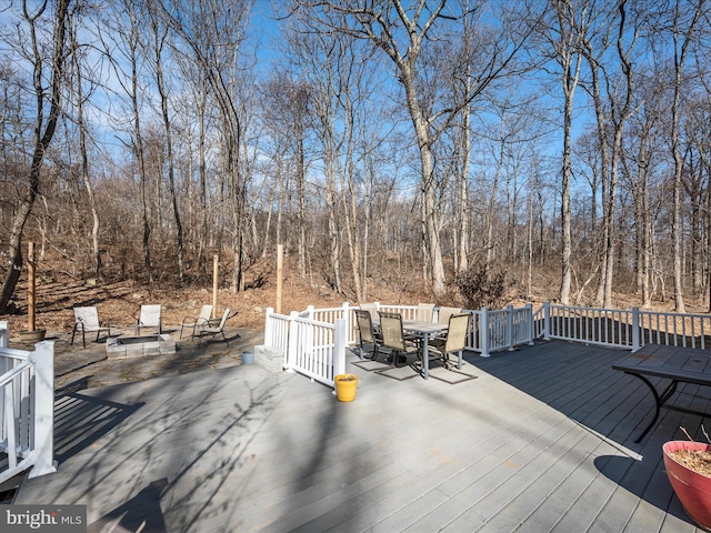 wooden deck with outdoor dining space and a forest view