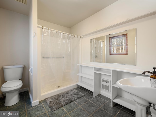 bathroom featuring a shower stall, toilet, baseboards, and a sink