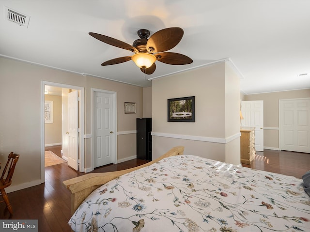 bedroom featuring visible vents, dark wood-type flooring, ceiling fan, baseboards, and ornamental molding