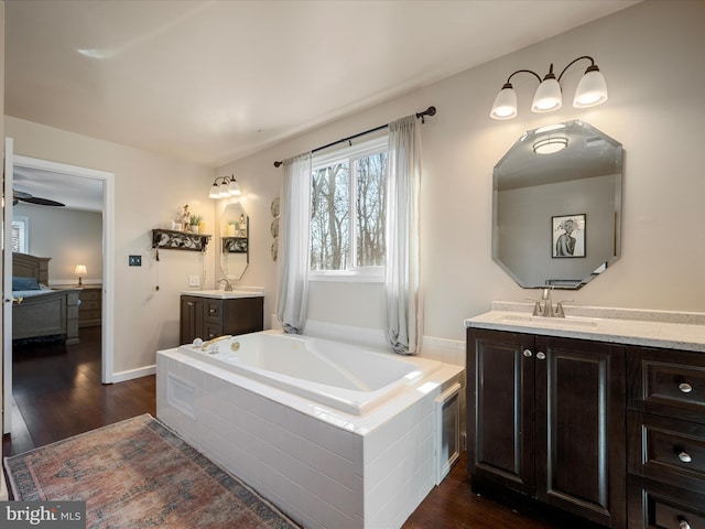 bathroom featuring ensuite bath, a bath, wood finished floors, and a sink