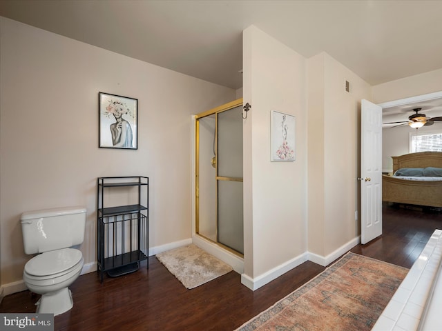 ensuite bathroom with baseboards, toilet, a stall shower, wood finished floors, and ensuite bath