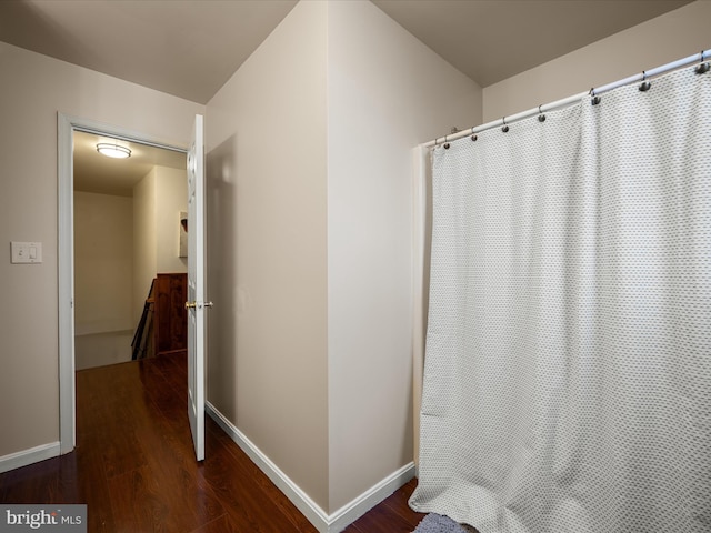 full bath with curtained shower, baseboards, and wood finished floors