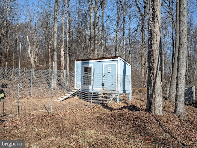 view of outdoor structure featuring entry steps, an outbuilding, and fence