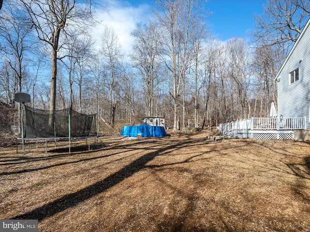 view of yard with a trampoline and a deck