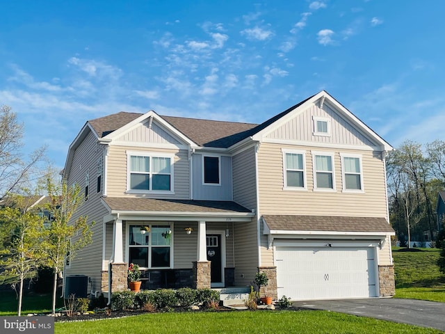 craftsman inspired home featuring cooling unit, aphalt driveway, board and batten siding, a porch, and a garage
