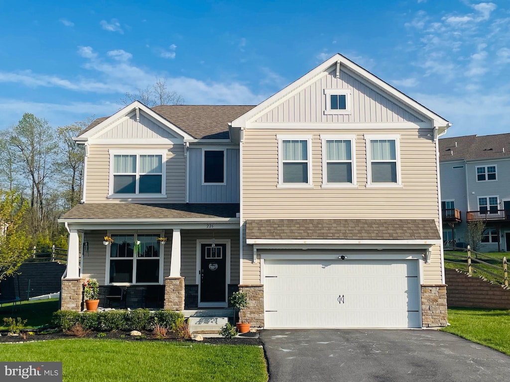craftsman-style house with a porch, a shingled roof, board and batten siding, aphalt driveway, and an attached garage