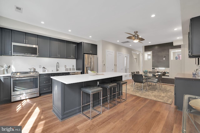 kitchen featuring light wood-style flooring, visible vents, a kitchen breakfast bar, light countertops, and appliances with stainless steel finishes