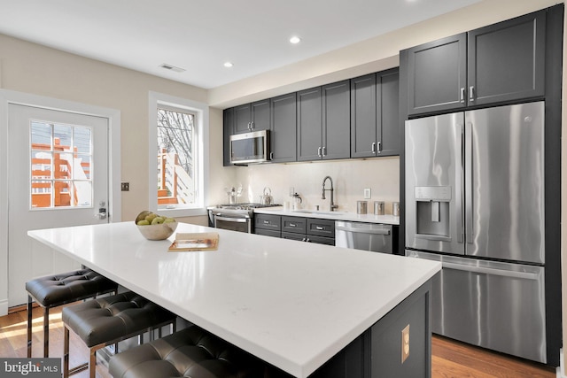 kitchen with a sink, visible vents, light countertops, appliances with stainless steel finishes, and a center island