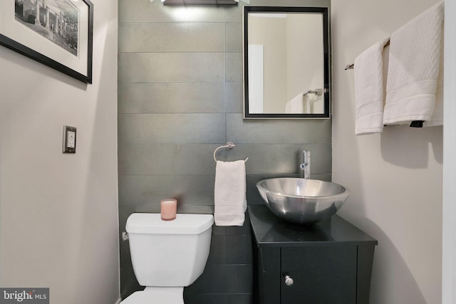 half bathroom with toilet, tile walls, and vanity