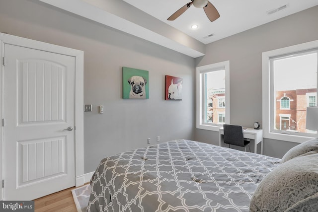 bedroom featuring ceiling fan, built in desk, wood finished floors, and visible vents