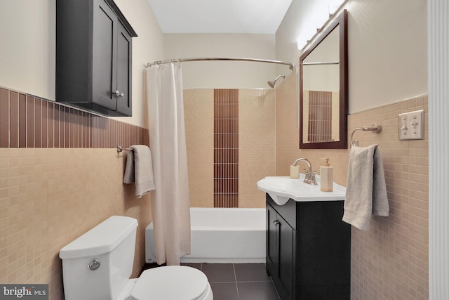 bathroom featuring toilet, a wainscoted wall, tile walls, and tile patterned floors