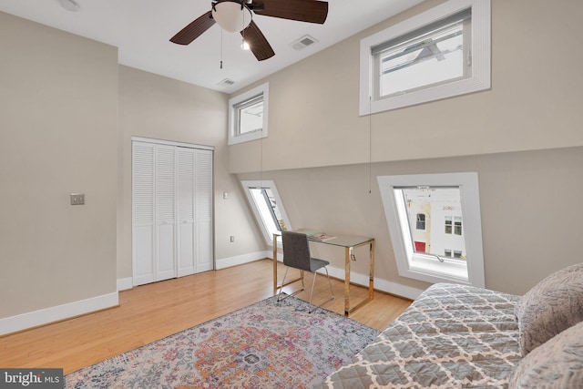 bedroom featuring a towering ceiling, baseboards, visible vents, and wood finished floors